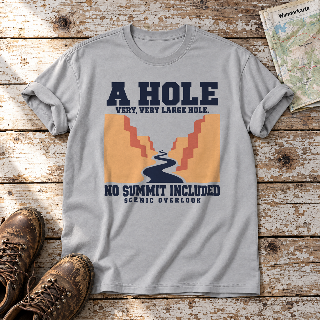 No Summit Included – T-Shirt Unisex in Hellgrau, flach liegend auf alten Holzbrettern mit Wanderschuhen und Wanderkarte.