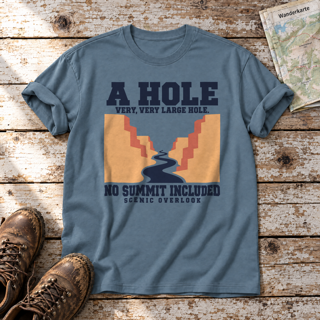 No Summit Included – T-Shirt Unisex in Steinblau, flach liegend auf alten Holzbrettern mit Wanderschuhen und Wanderkarte.