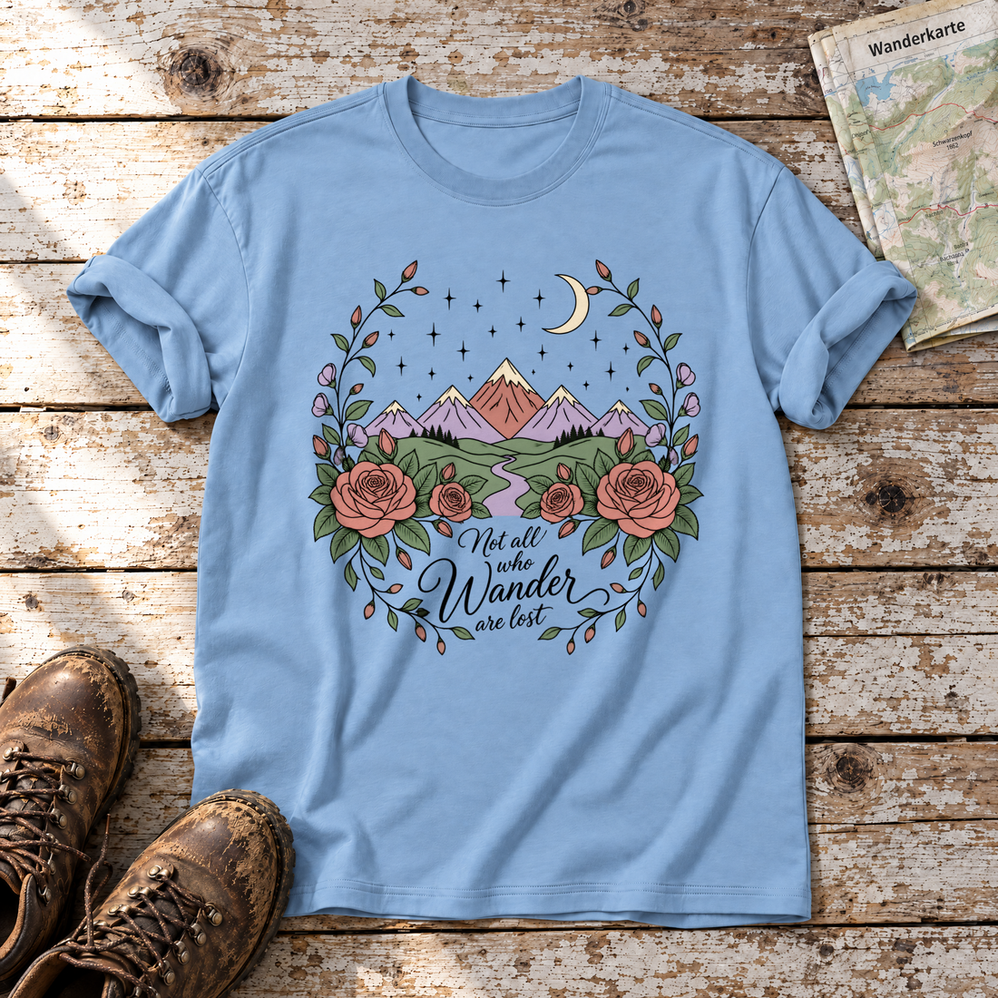 Not all who Wander are lost – T-Shirt Unisex in Himmelblau, flach liegend auf alten Holzbrettern mit Wanderschuhen und Wanderkarte.