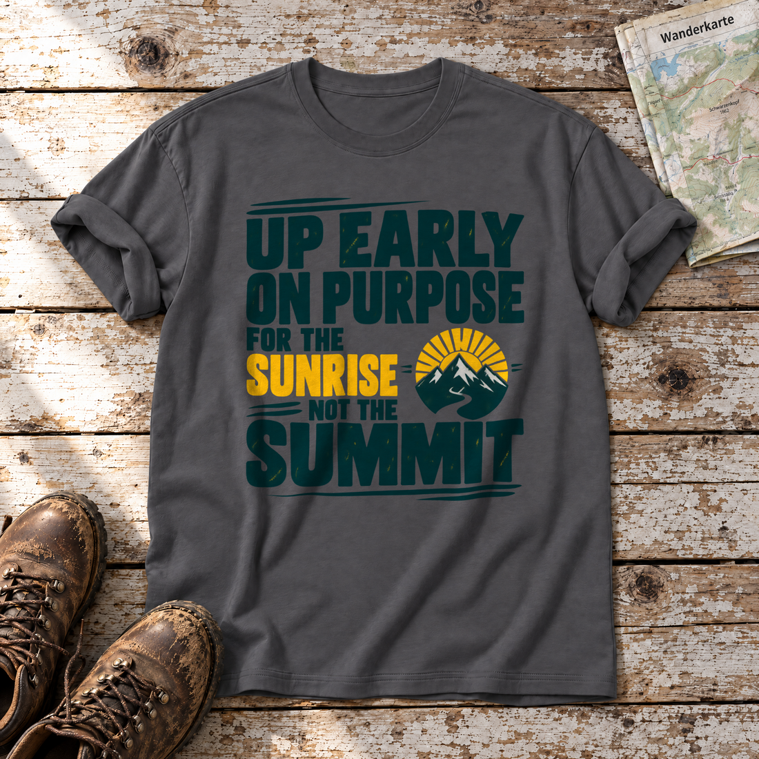 For the Sunrise, Not the Summit – T-Shirt Unisex in Dunkelgrau, flach liegend auf alten Holzbrettern mit Wanderschuhen und Wanderkarte.