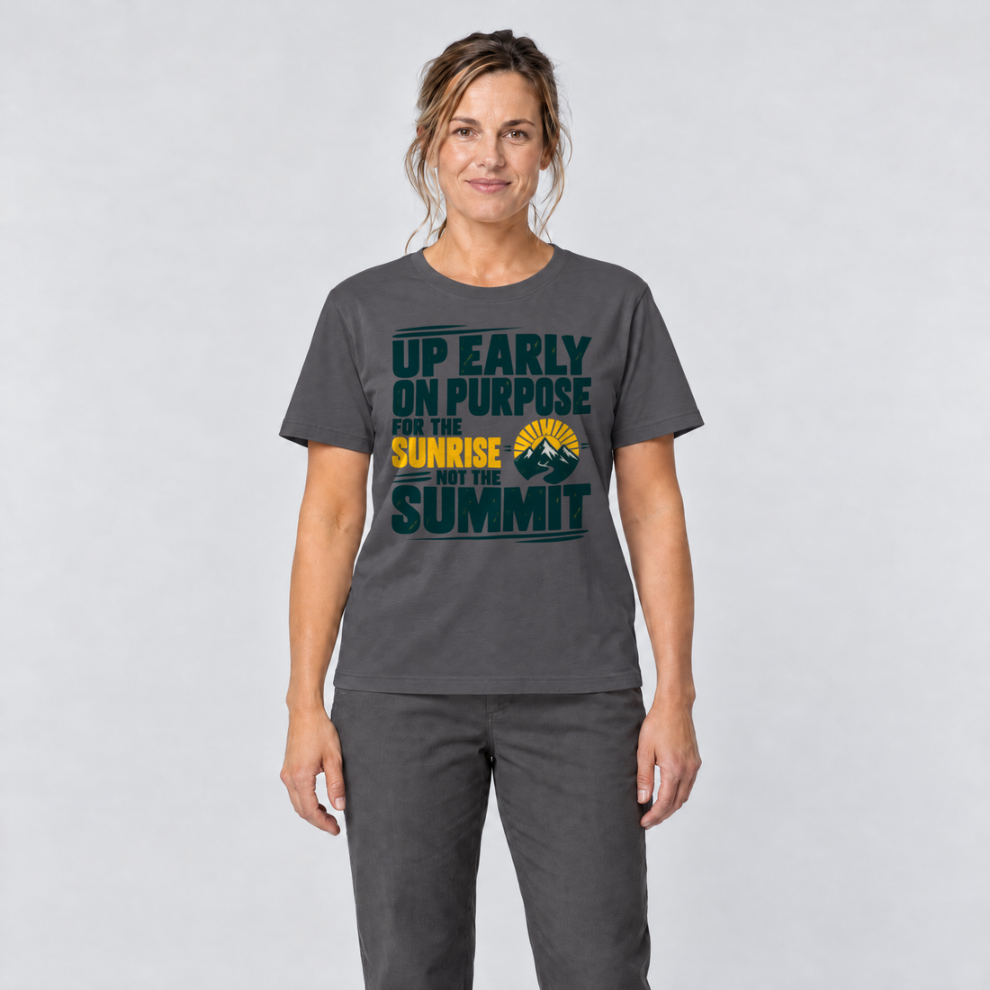 Frau trägt For the Sunrise, Not the Summit – T-Shirt Unisex in Dunkelgrau, Ansicht von vorn