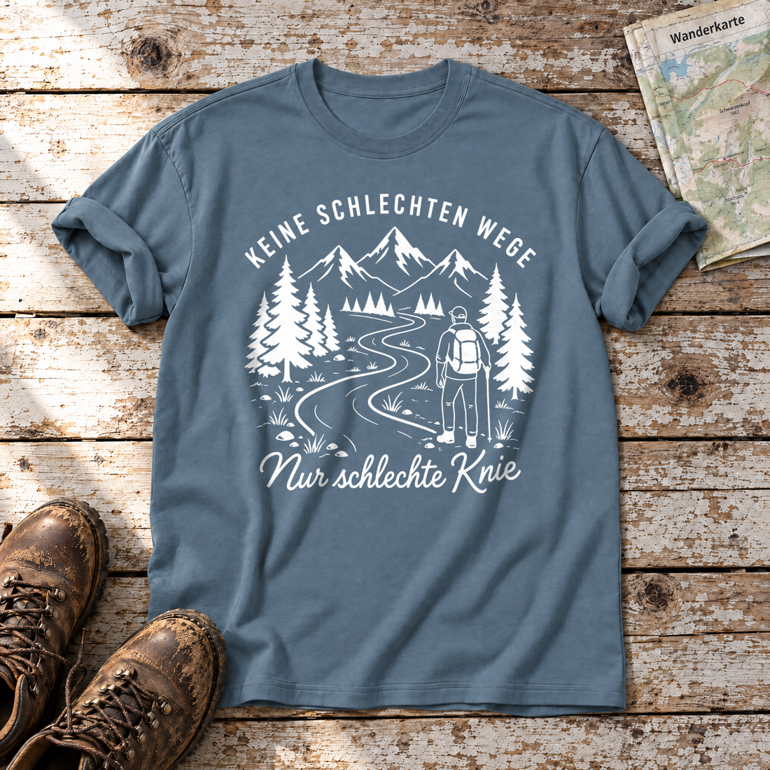 Nur schlechte Knie – T-Shirt Unisex in Steinblau, flach liegend auf alten Holzbrettern mit Wanderschuhen und Wanderkarte.