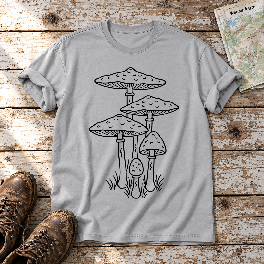 Parasolpilze – T-Shirt Unisex in Hellgrau, flach liegend auf alten Holzbrettern mit Wanderschuhen und Wanderkarte.