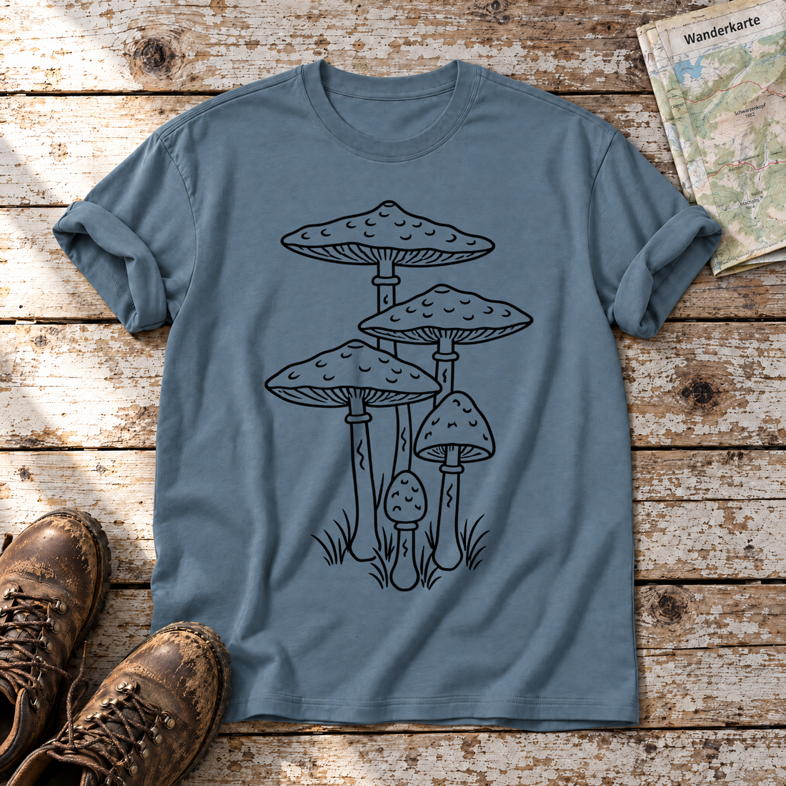 Parasolpilze – T-Shirt Unisex in Steinblau, flach liegend auf alten Holzbrettern mit Wanderschuhen und Wanderkarte.