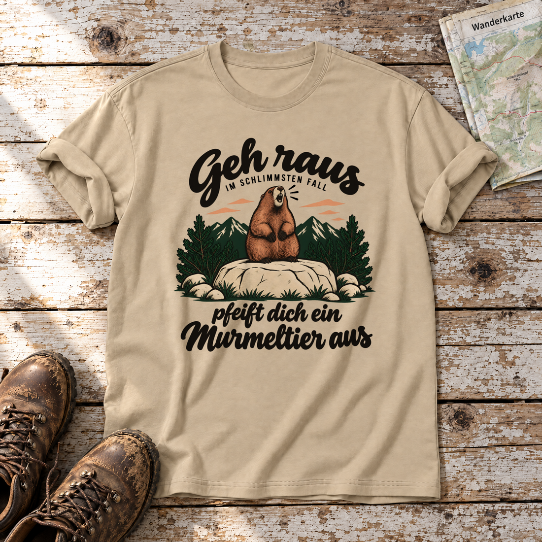 Pfeift dich ein Murmeltier aus – T-Shirt Unisex in Sand, flach liegend auf alten Holzbrettern mit Wanderschuhen und Wanderkarte.