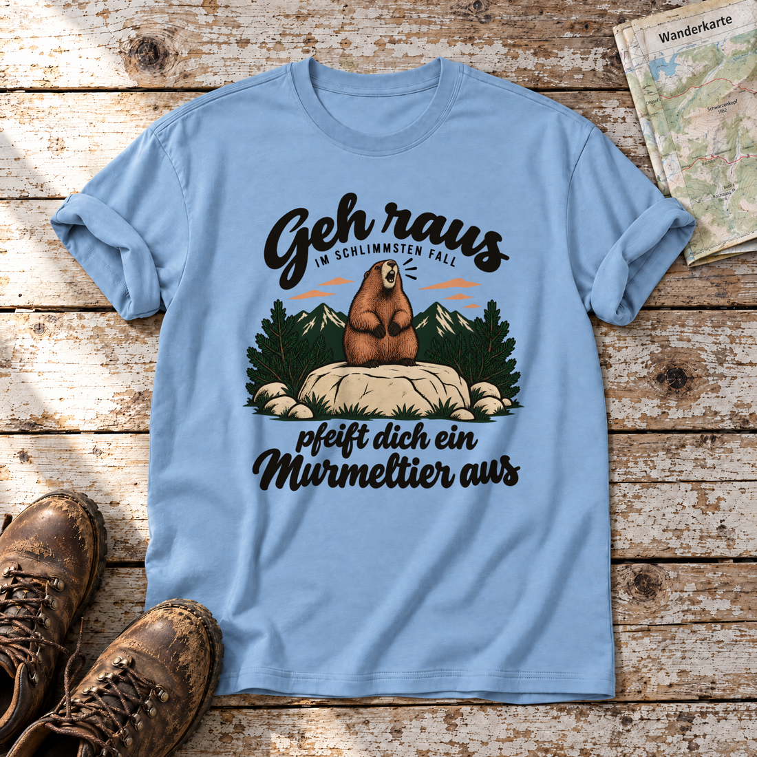 Pfeift dich ein Murmeltier aus – T-Shirt Unisex in Himmelblau, flach liegend auf alten Holzbrettern mit Wanderschuhen und Wanderkarte.