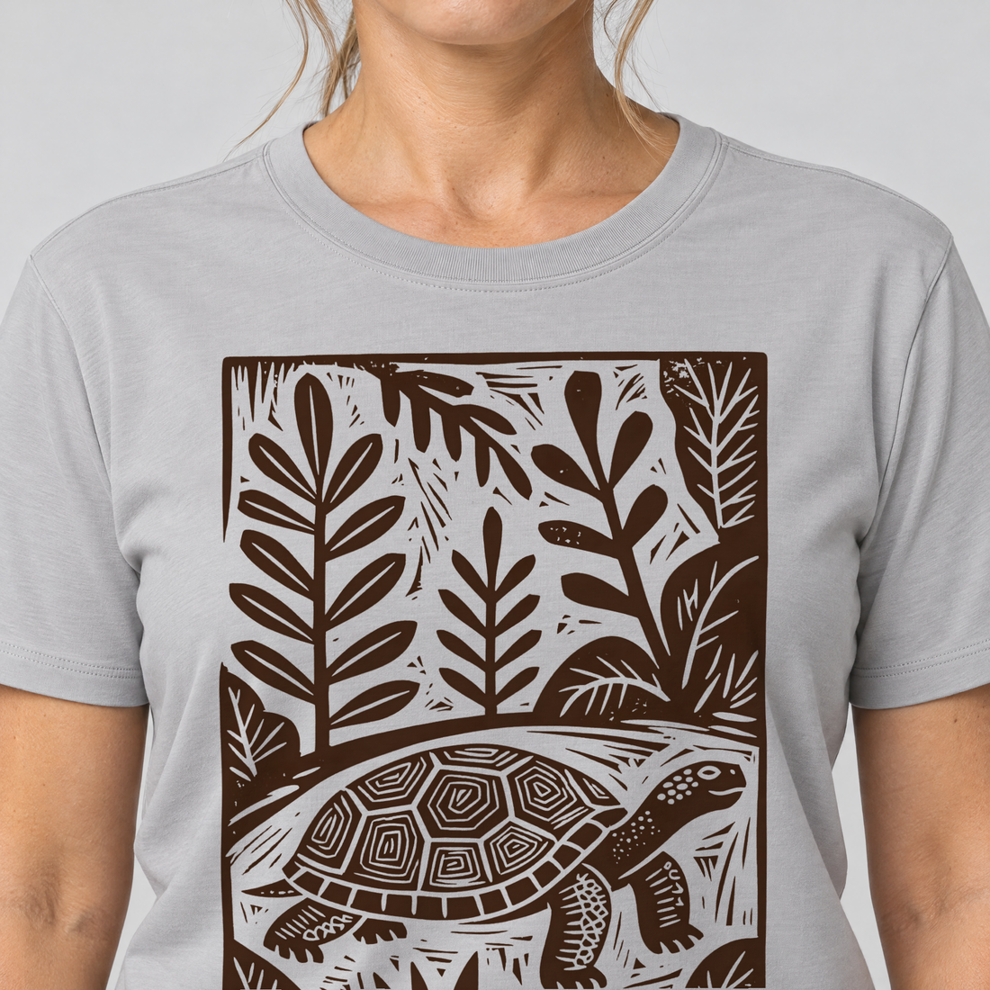 Nahaufnahme des Drucks: Schildkröte im Linolschnitt – T-Shirt Unisex in Hellgrau, von einer Frau getragen