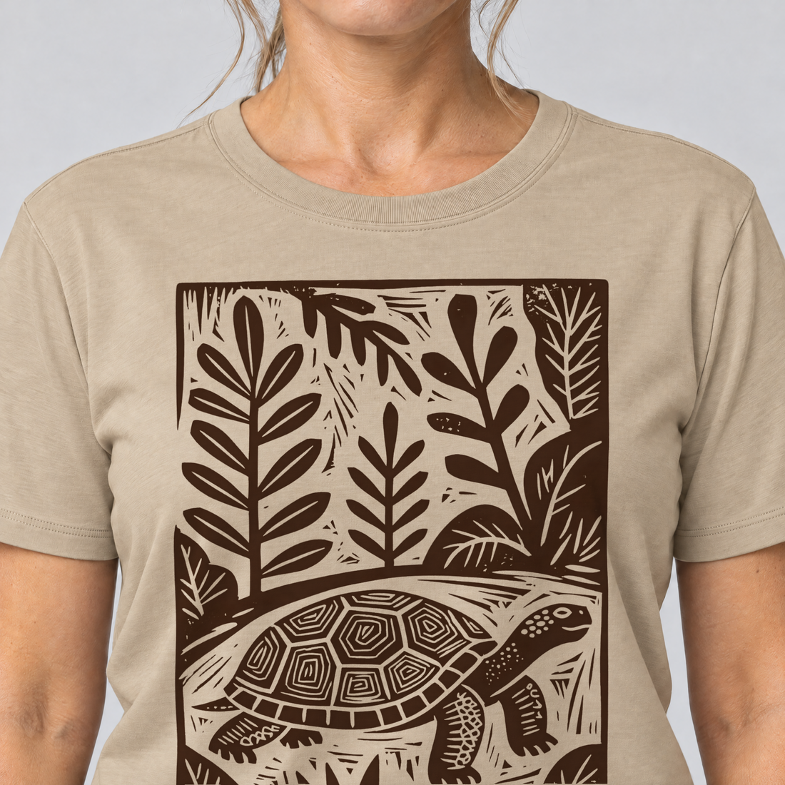 Nahaufnahme des Drucks: Schildkröte im Linolschnitt – T-Shirt Unisex in Sand, von einer Frau getragen