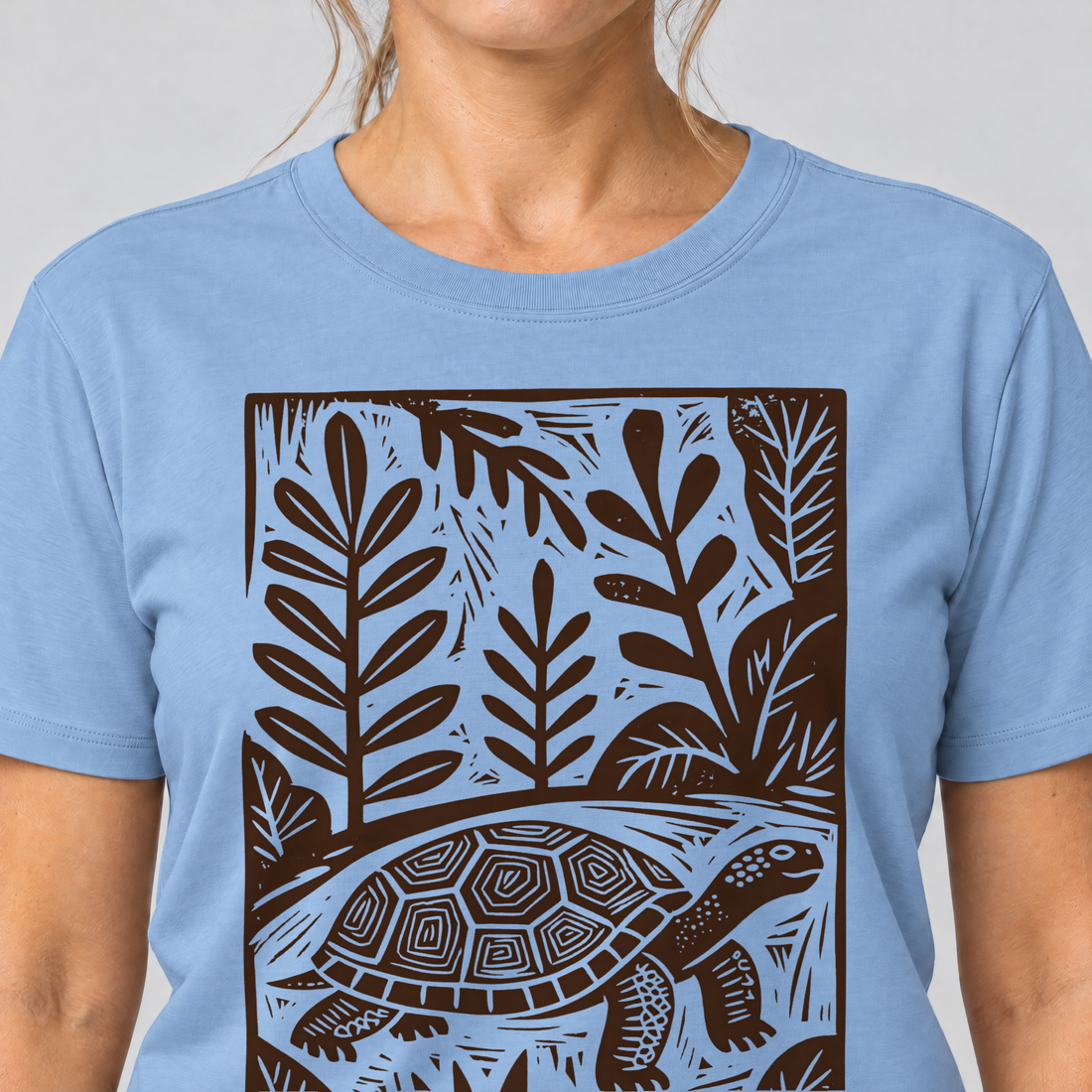 Nahaufnahme des Drucks: Schildkröte im Linolschnitt – T-Shirt Unisex in Himmelblau, von einer Frau getragen