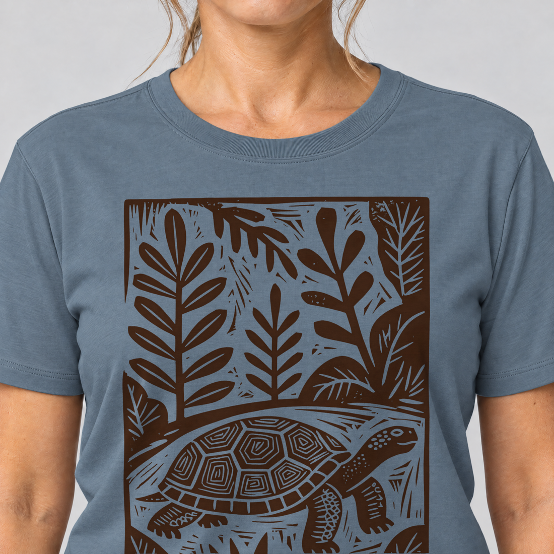 Nahaufnahme des Drucks: Schildkröte im Linolschnitt – T-Shirt Unisex in Steinblau, von einer Frau getragen