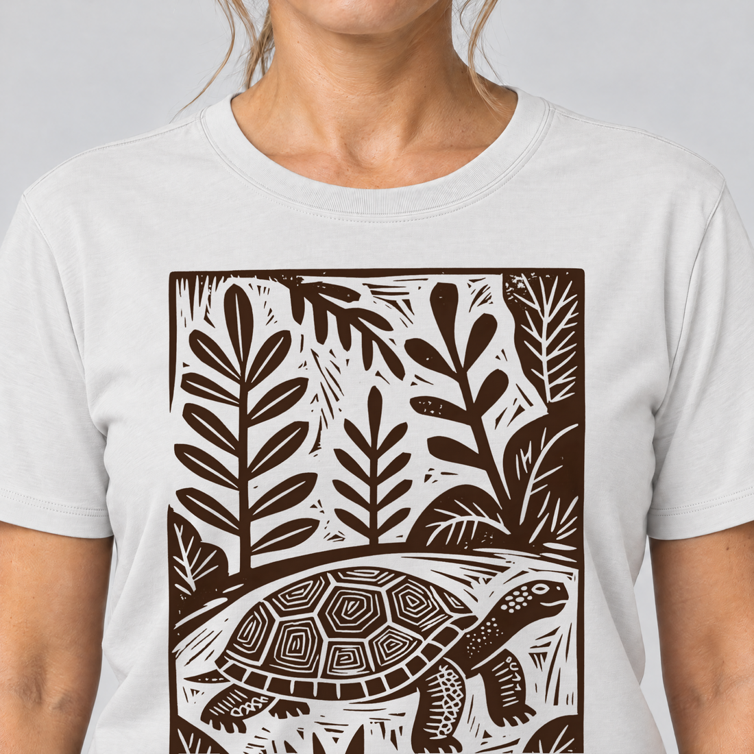 Nahaufnahme des Drucks: Schildkröte im Linolschnitt – T-Shirt Unisex in Weiß, von einer Frau getragen