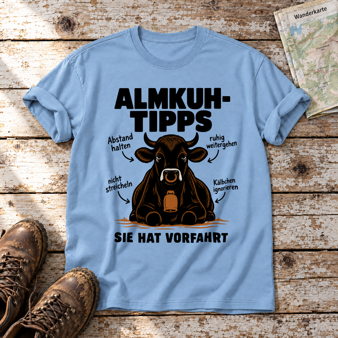 Sie hat Vorfahrt – T-Shirt Unisex in Himmelblau, flach liegend auf alten Holzbrettern mit Wanderschuhen und Wanderkarte.
