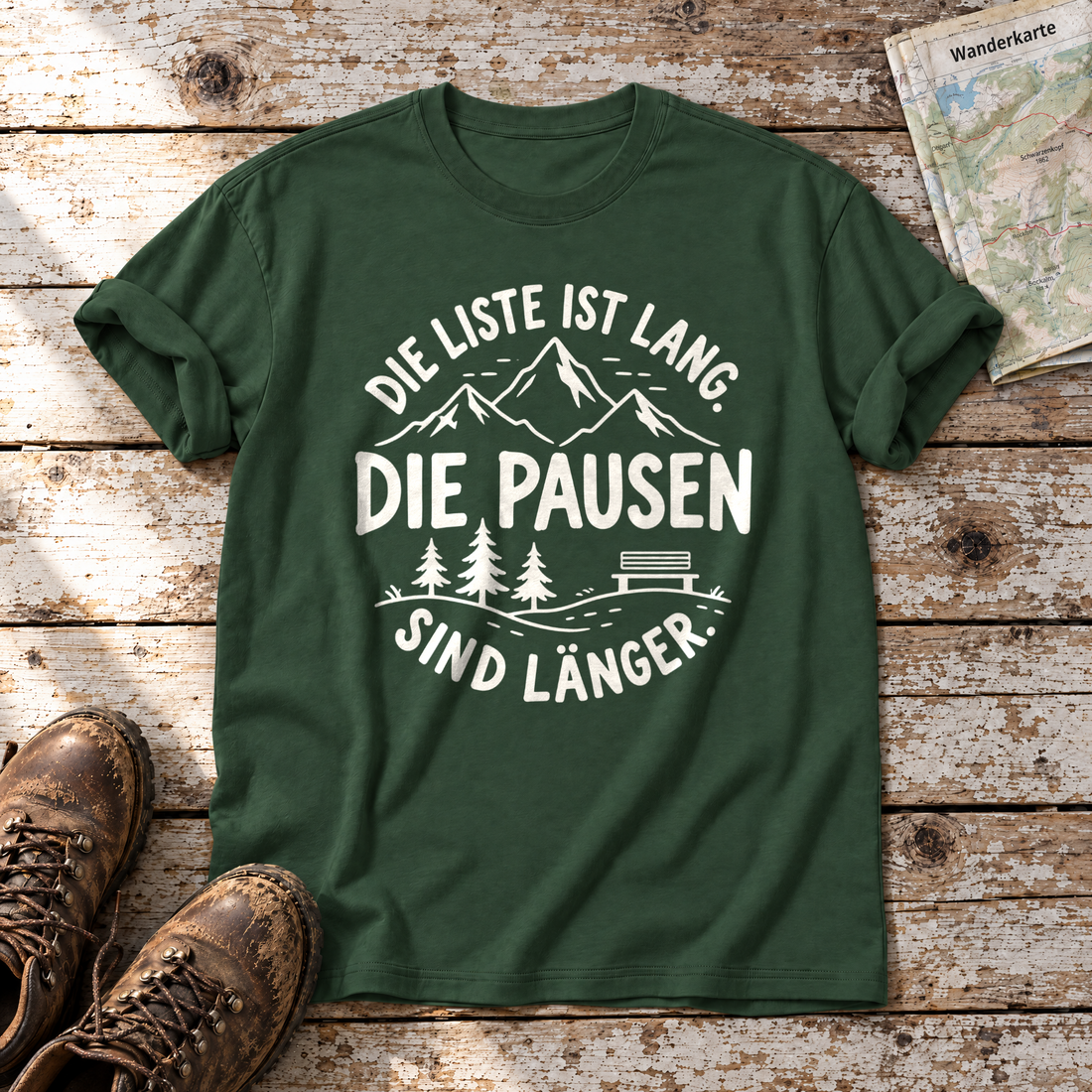 Die Pausen sind länger – T-Shirt Unisex in Flaschengrün, flach liegend auf alten Holzbrettern mit Wanderschuhen und Wanderkarte.