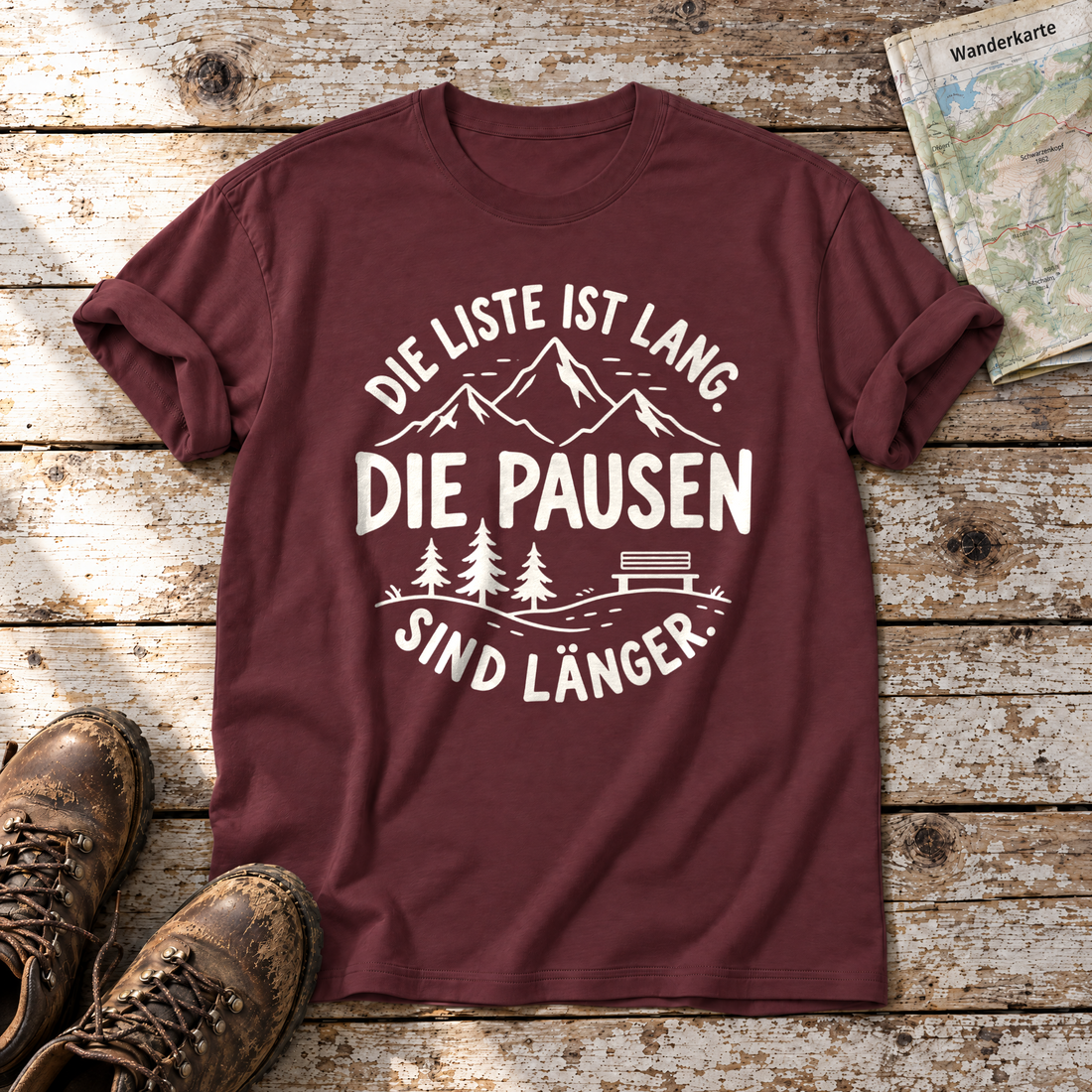 Die Pausen sind länger – T-Shirt Unisex in Bordeaux, flach liegend auf alten Holzbrettern mit Wanderschuhen und Wanderkarte.