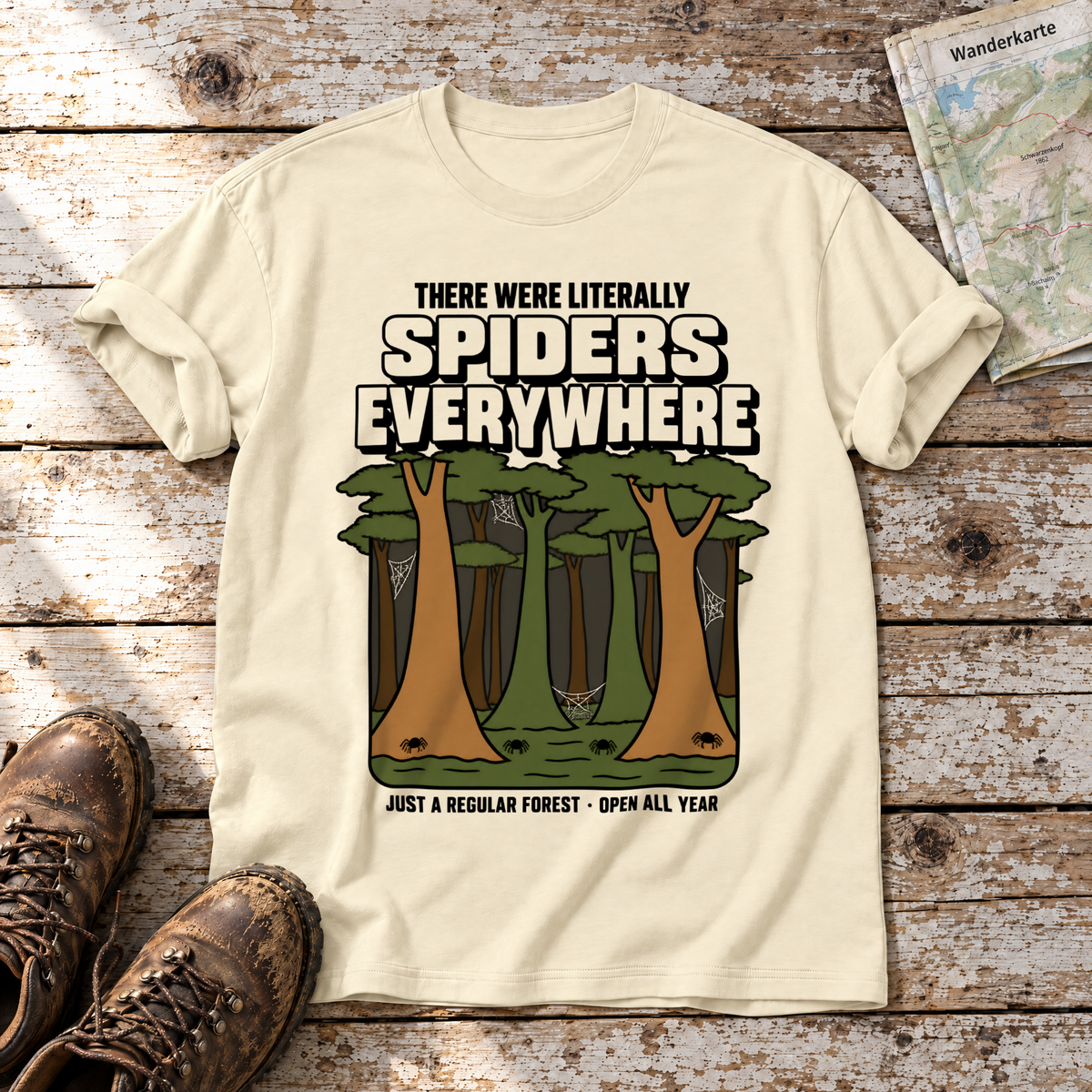Literally Spiders Everywhere – T-Shirt Unisex in Natur, flach liegend auf alten Holzbrettern mit Wanderschuhen und Wanderkarte.