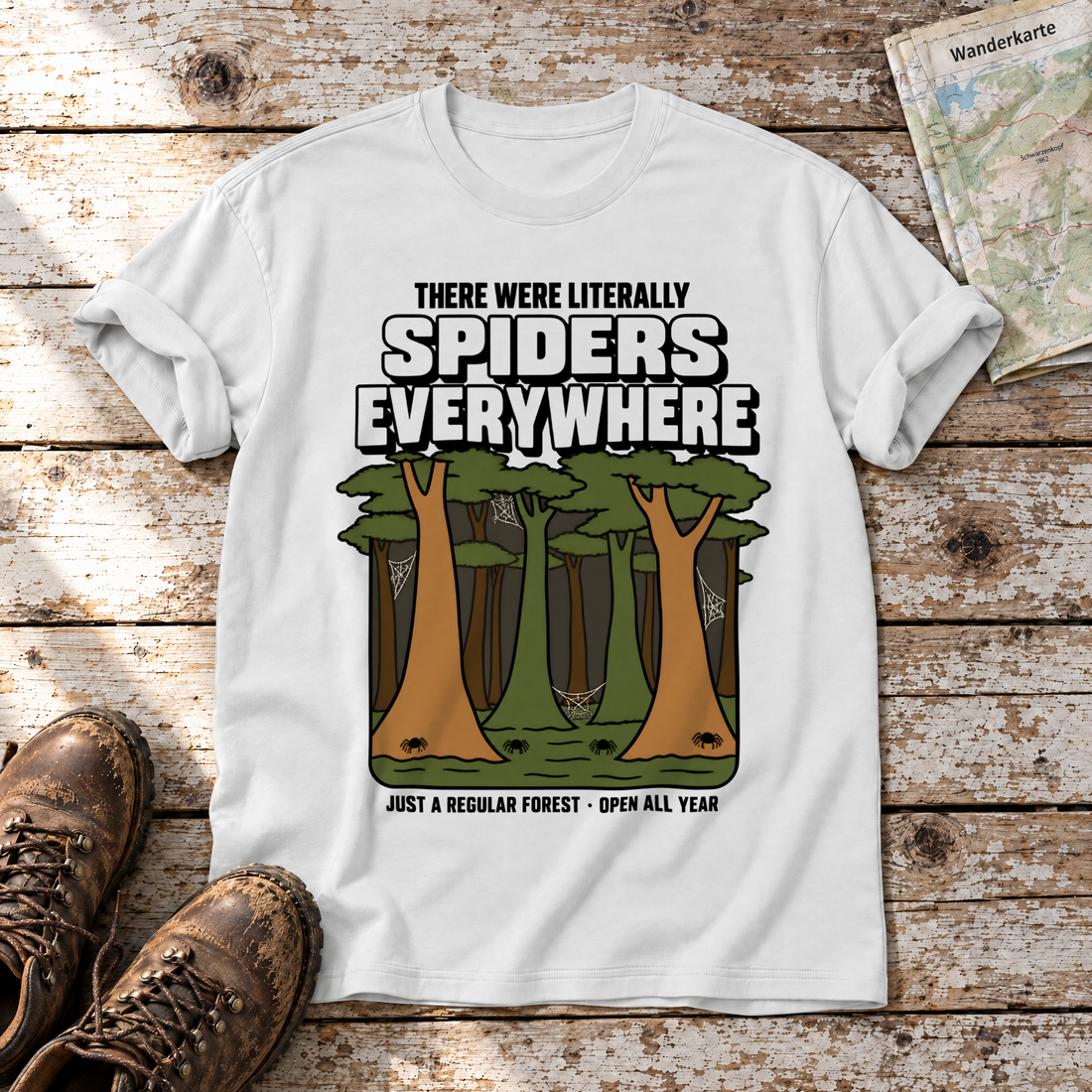 Literally Spiders Everywhere – T-Shirt Unisex in Weiß, flach liegend auf alten Holzbrettern mit Wanderschuhen und Wanderkarte.