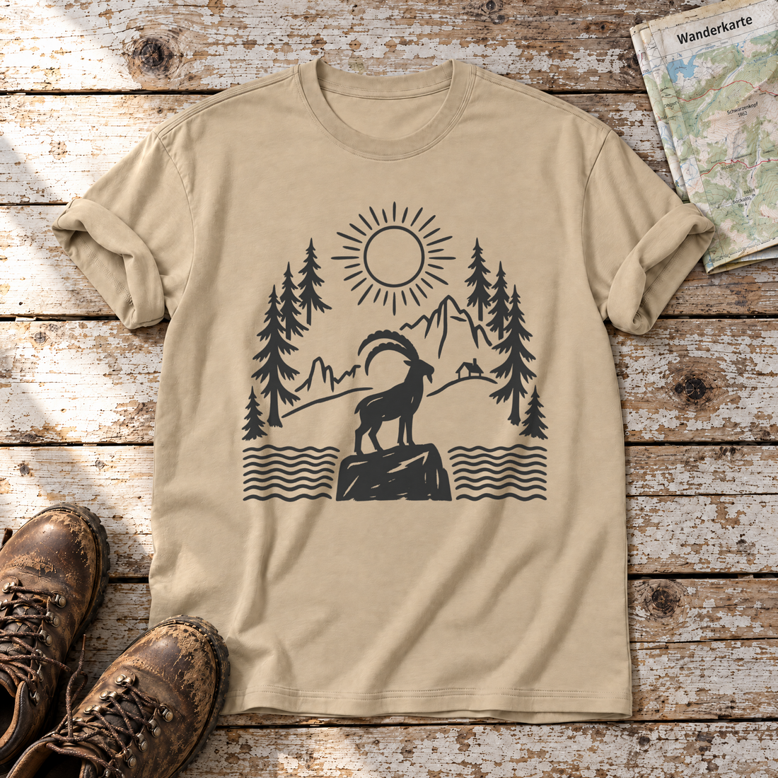 Steinbock am Bergsee – T-Shirt Unisex in Sand, flach liegend auf alten Holzbrettern mit Wanderschuhen und Wanderkarte.