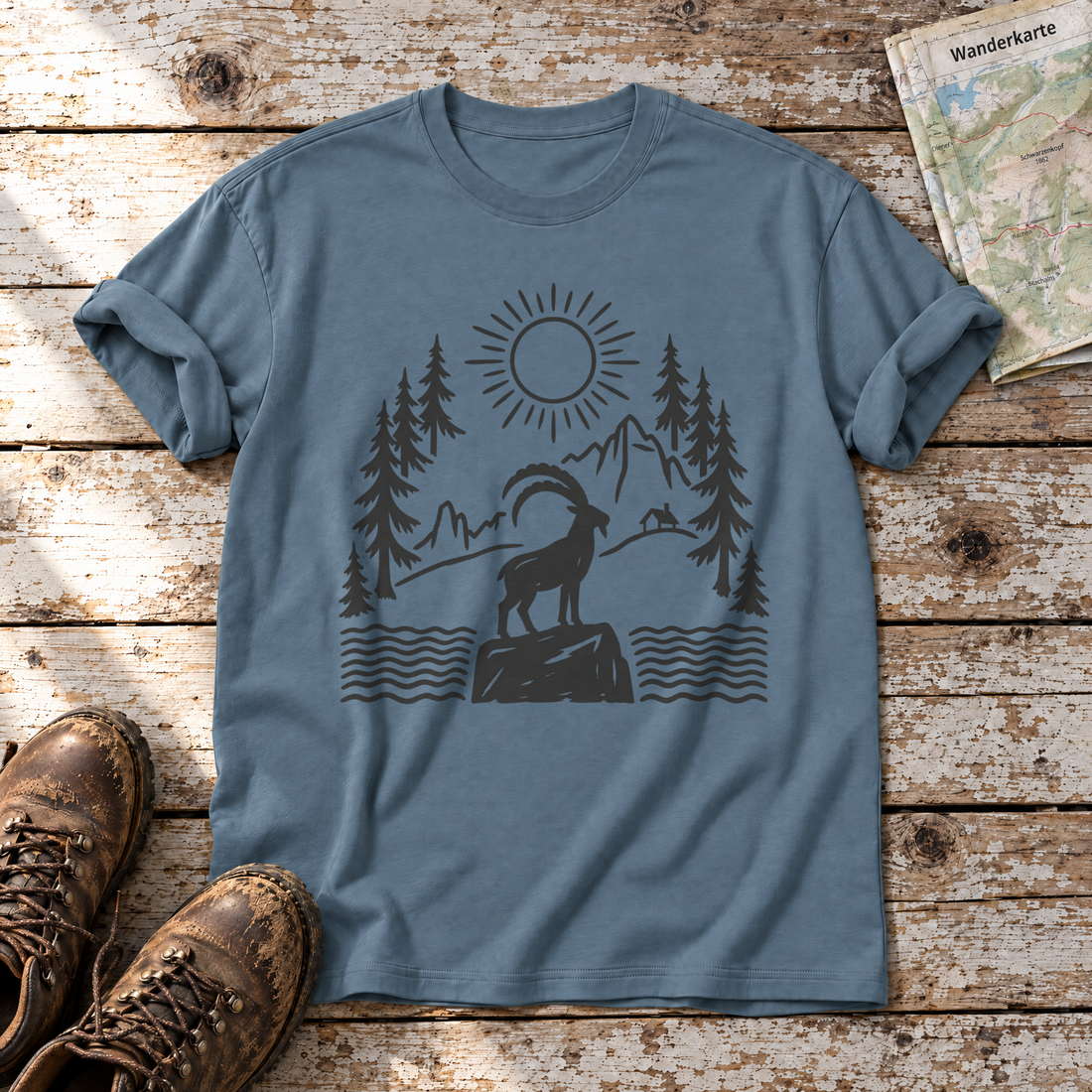 Steinbock am Bergsee – T-Shirt Unisex in Steinblau, flach liegend auf alten Holzbrettern mit Wanderschuhen und Wanderkarte.