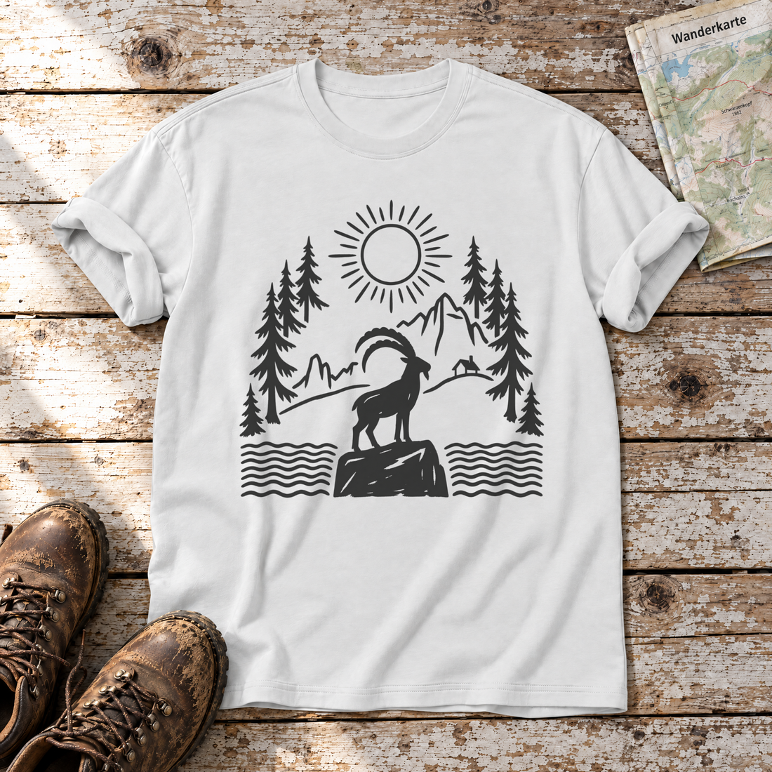 Steinbock am Bergsee – T-Shirt Unisex in Weiß, flach liegend auf alten Holzbrettern mit Wanderschuhen und Wanderkarte.