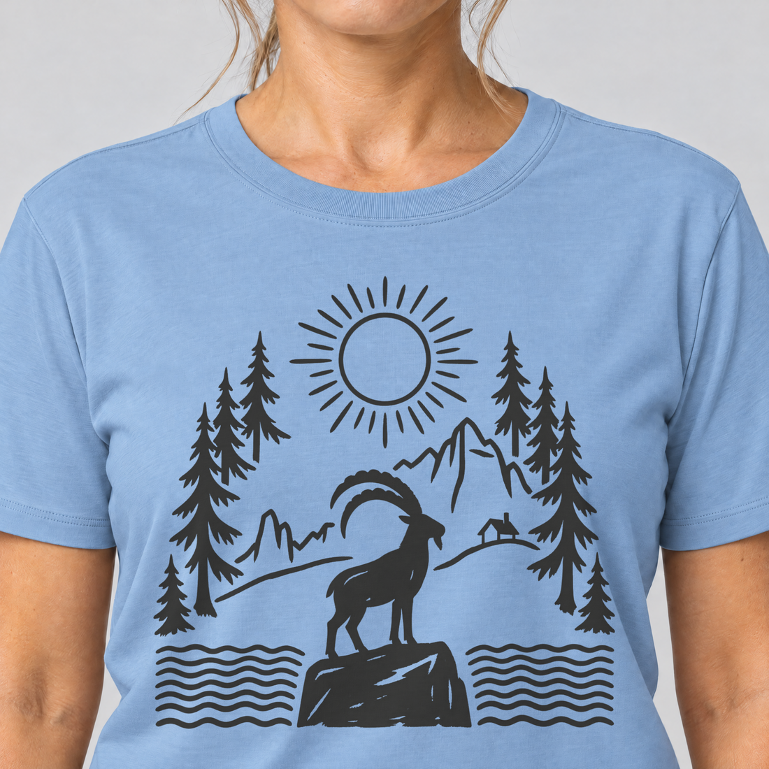 Nahaufnahme des Drucks: Steinbock am Bergsee – T-Shirt Unisex in Himmelblau, von einer Frau getragen