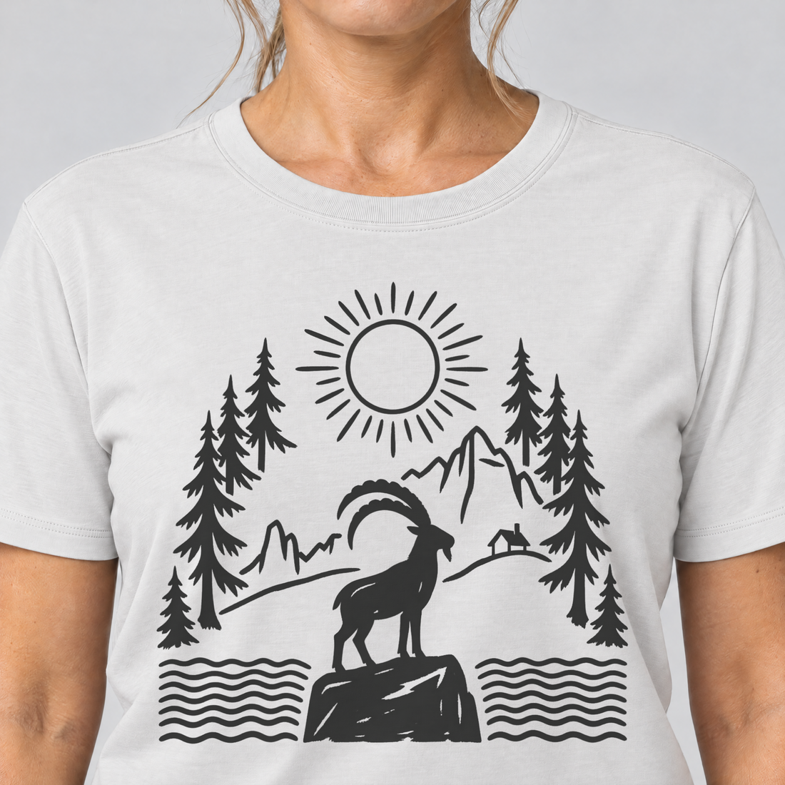 Nahaufnahme des Drucks: Steinbock am Bergsee – T-Shirt Unisex in Weiß, von einer Frau getragen