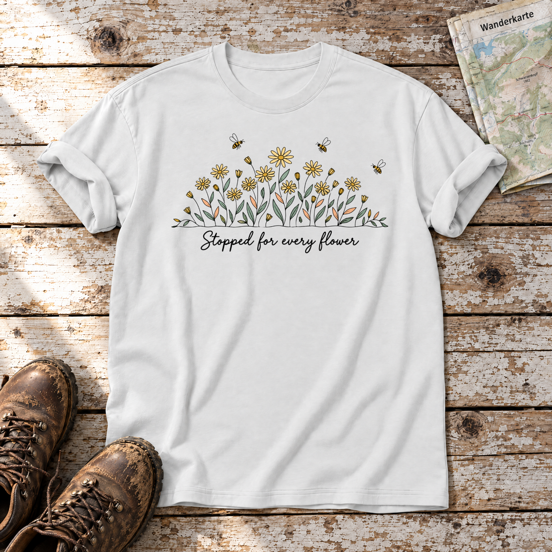 Stopped for every flower – T-Shirt Unisex in Weiß, flach liegend auf alten Holzbrettern mit Wanderschuhen und Wanderkarte.