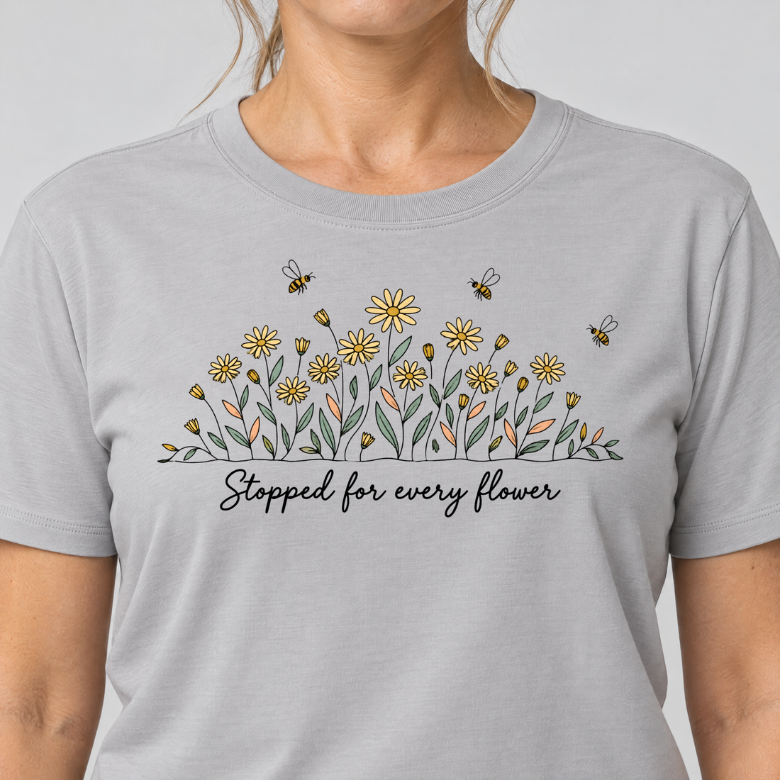 Nahaufnahme des Drucks: Stopped for every flower – T-Shirt Unisex in Hellgrau, von einer Frau getragen