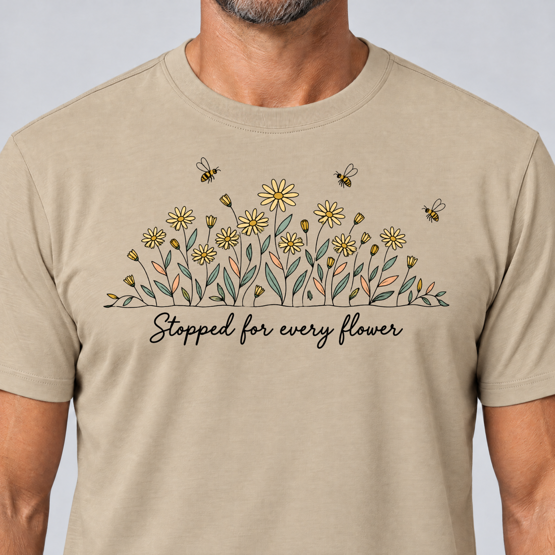 Nahaufnahme des Drucks: Stopped for every flower – T-Shirt Unisex in Sand, von einem Mann getragen