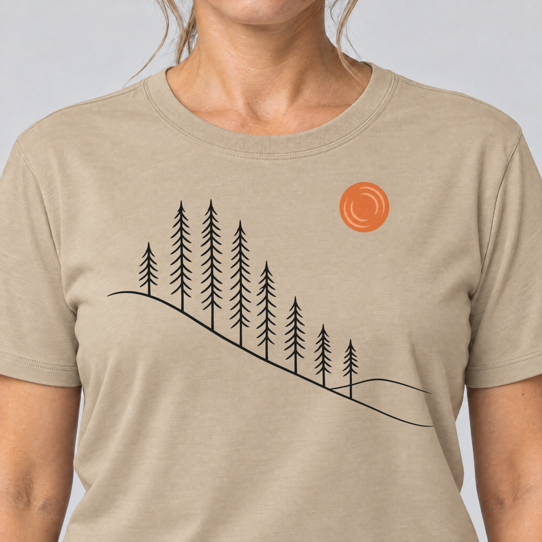 Nahaufnahme des Drucks: Tannenhang – T-Shirt Unisex in Sand, von einer Frau getragen
