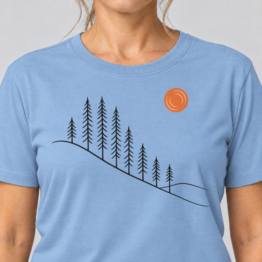 Nahaufnahme des Drucks: Tannenhang – T-Shirt Unisex in Himmelblau, von einer Frau getragen