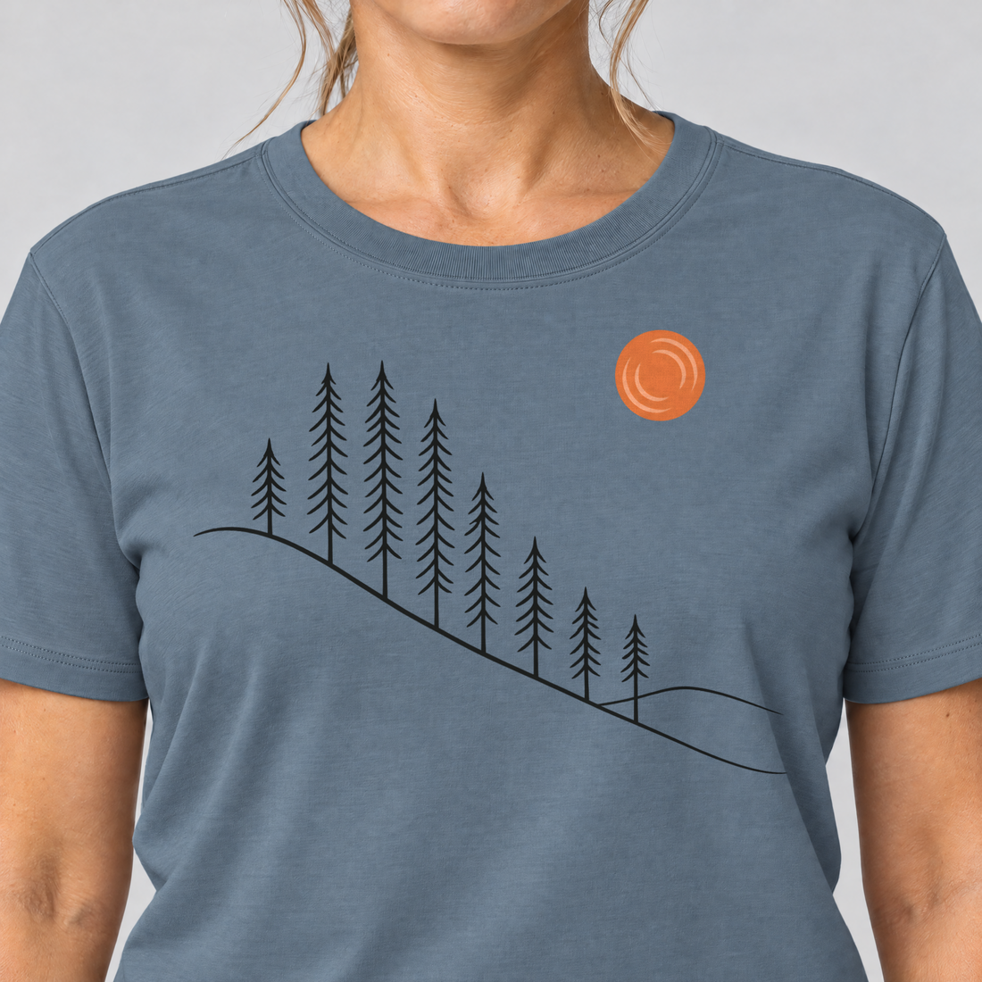 Nahaufnahme des Drucks: Tannenhang – T-Shirt Unisex in Steinblau, von einer Frau getragen