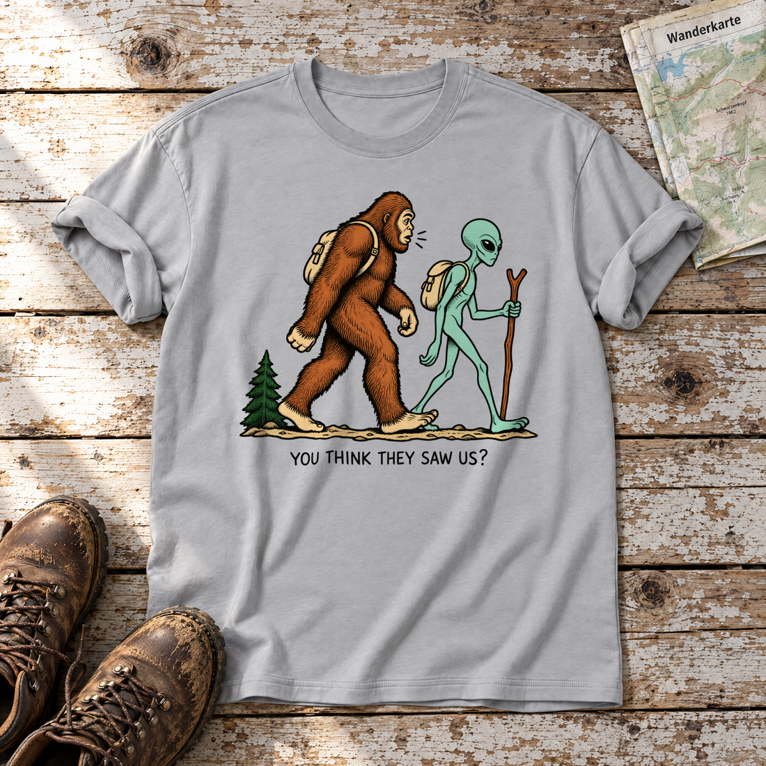 Think they saw us? – T-Shirt Unisex in Hellgrau, flach liegend auf alten Holzbrettern mit Wanderschuhen und Wanderkarte.