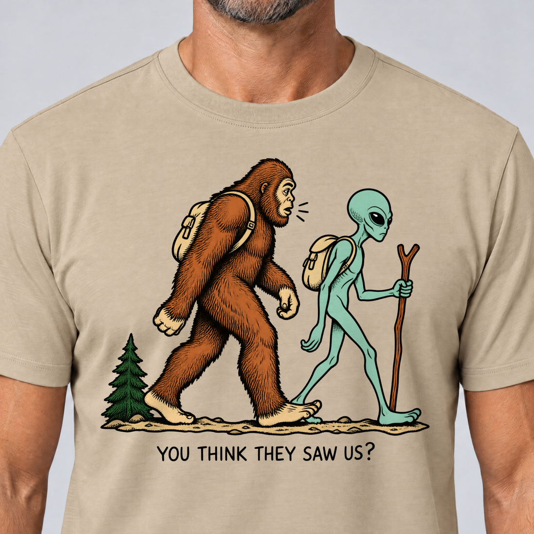 Nahaufnahme des Drucks: Think they saw us? – T-Shirt Unisex in Sand, von einem Mann getragen