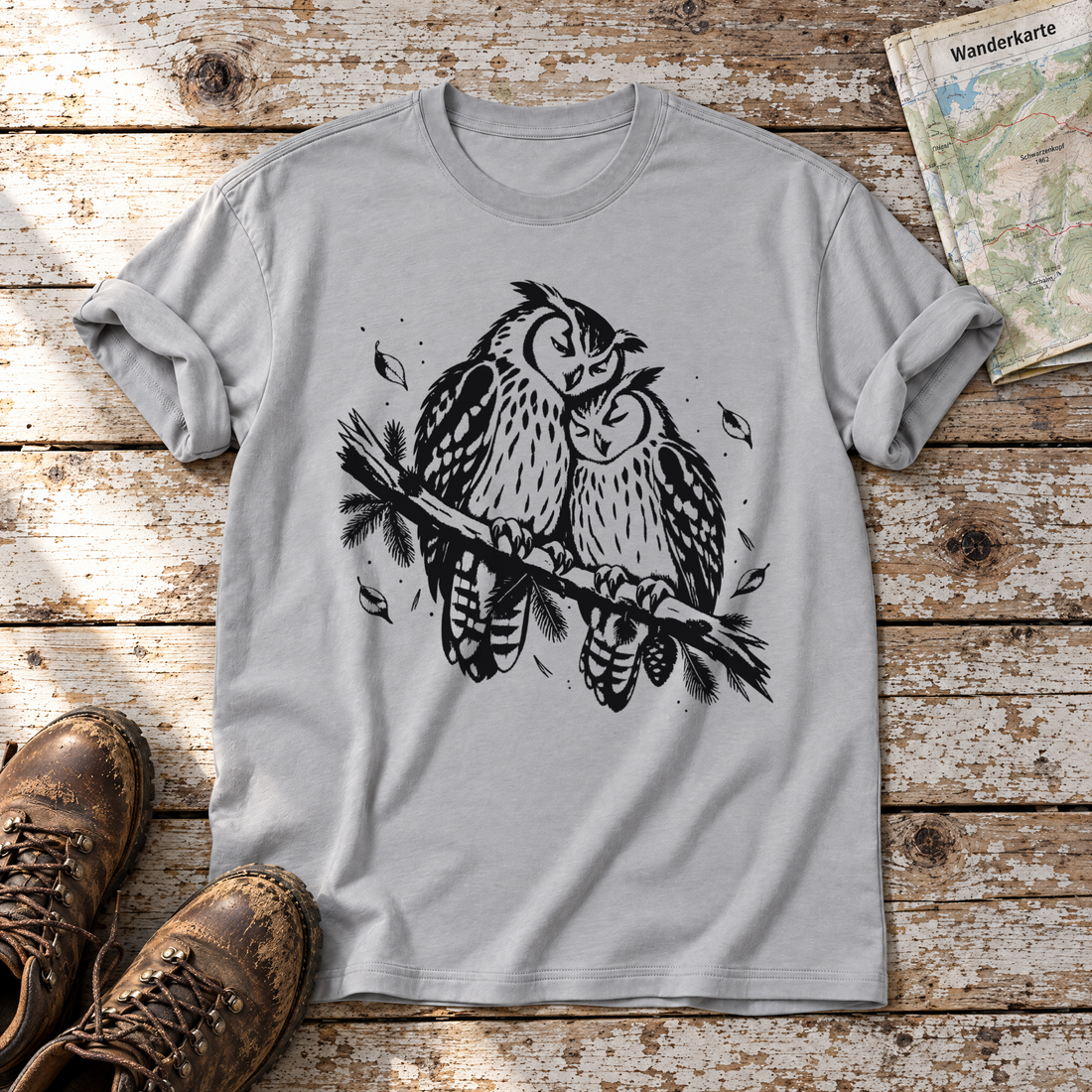 Uhupaar auf dem Fichtenast – T-Shirt Unisex in Hellgrau, flach liegend auf alten Holzbrettern mit Wanderschuhen und Wanderkarte.