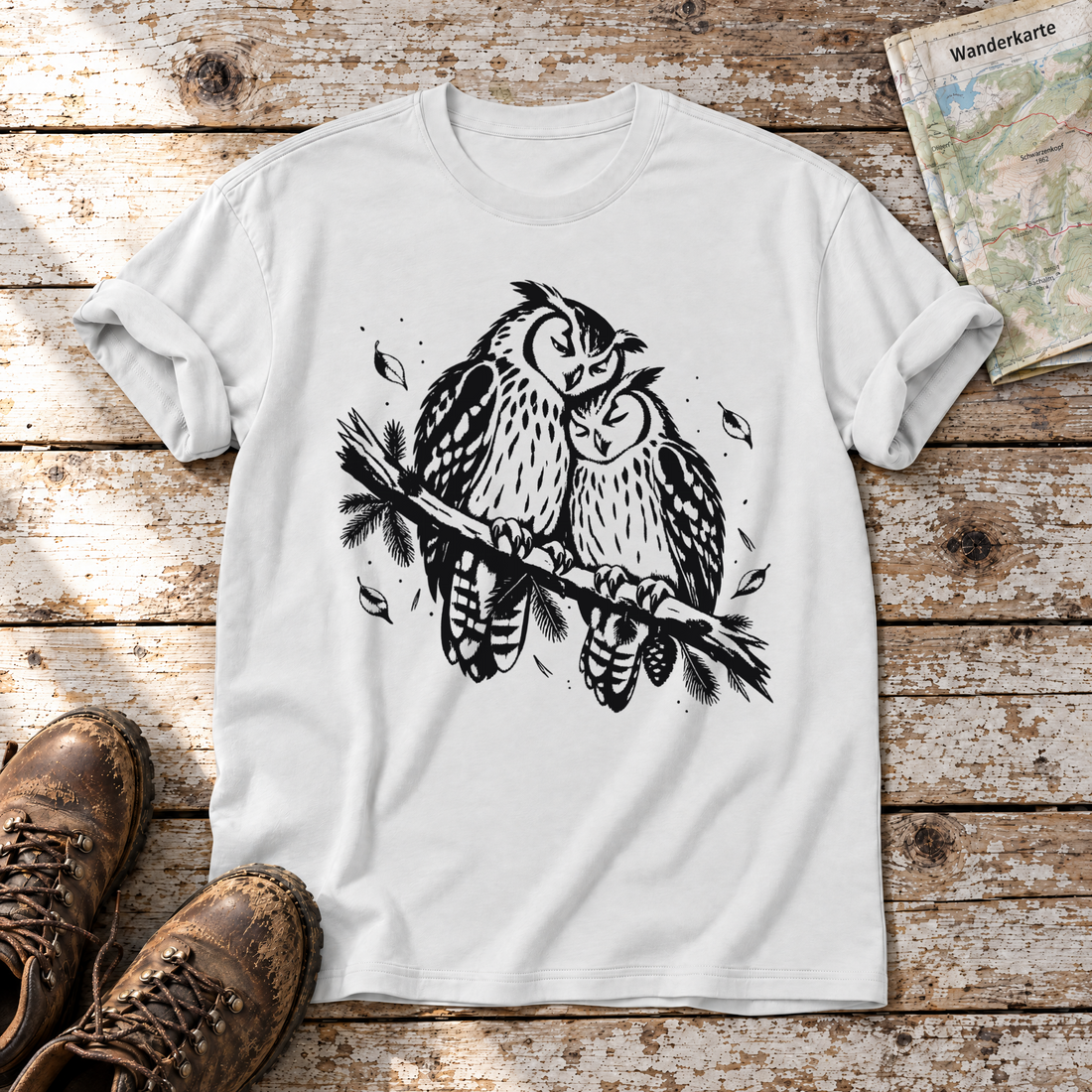 Uhupaar auf dem Fichtenast – T-Shirt Unisex in Weiß, flach liegend auf alten Holzbrettern mit Wanderschuhen und Wanderkarte.