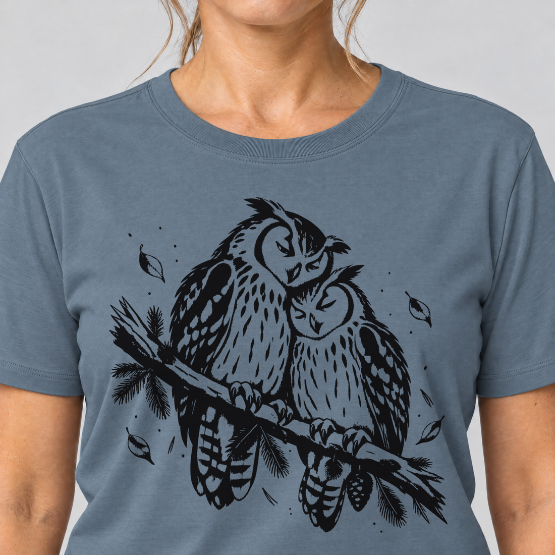 Nahaufnahme des Drucks: Uhupaar auf dem Fichtenast – T-Shirt Unisex in Steinblau, von einer Frau getragen