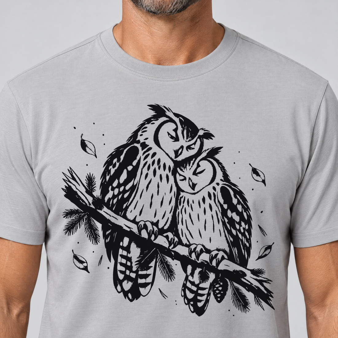 Nahaufnahme des Drucks: Uhupaar auf dem Fichtenast – T-Shirt Unisex in Hellgrau, von einem Mann getragen