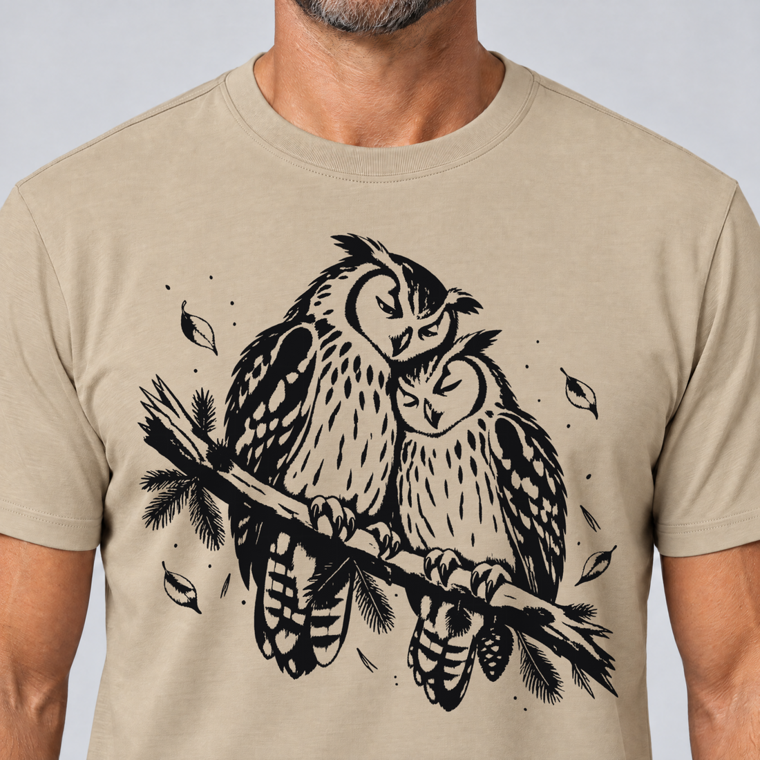 Nahaufnahme des Drucks: Uhupaar auf dem Fichtenast – T-Shirt Unisex in Sand, von einem Mann getragen