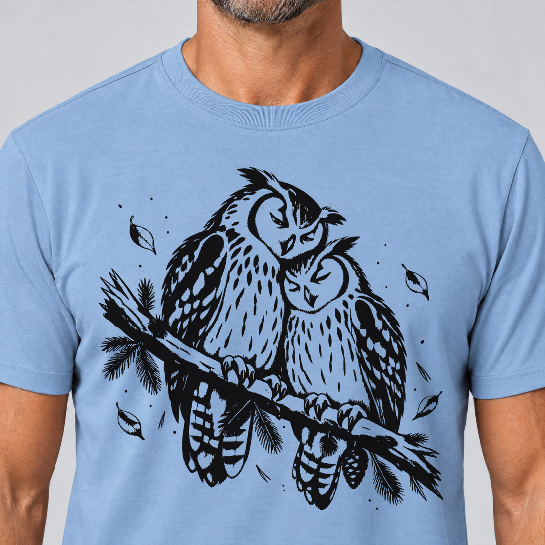 Nahaufnahme des Drucks: Uhupaar auf dem Fichtenast – T-Shirt Unisex in Himmelblau, von einem Mann getragen