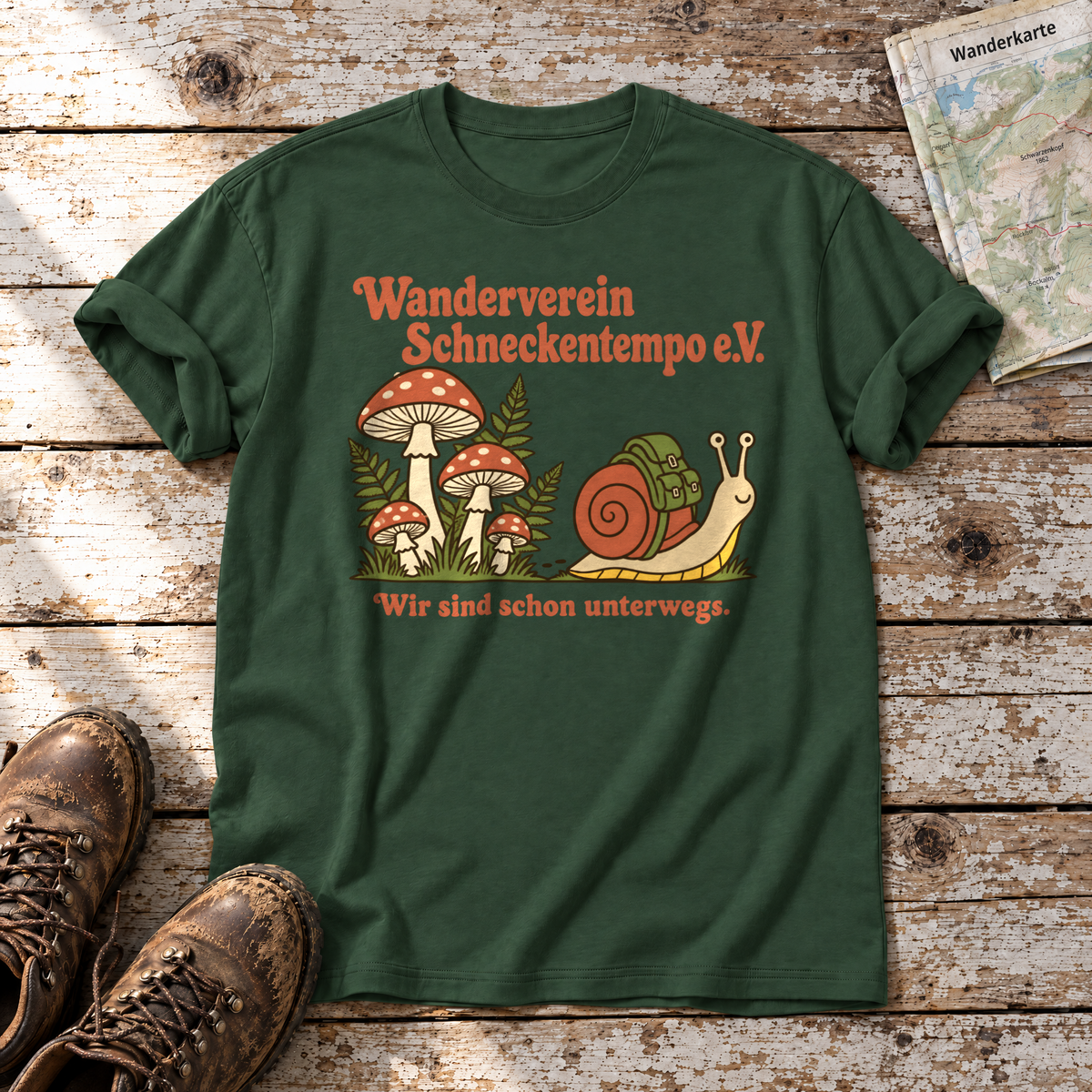 Wanderverein Schneckentempo – T-Shirt Unisex in Flaschengrün, flach liegend auf alten Holzbrettern mit Wanderschuhen und Wanderkarte.