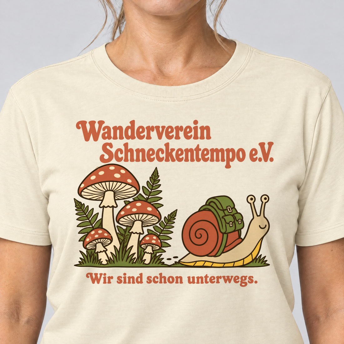 Nahaufnahme des Drucks: Wanderverein Schneckentempo – T-Shirt Unisex in Natur, von einer Frau getragen