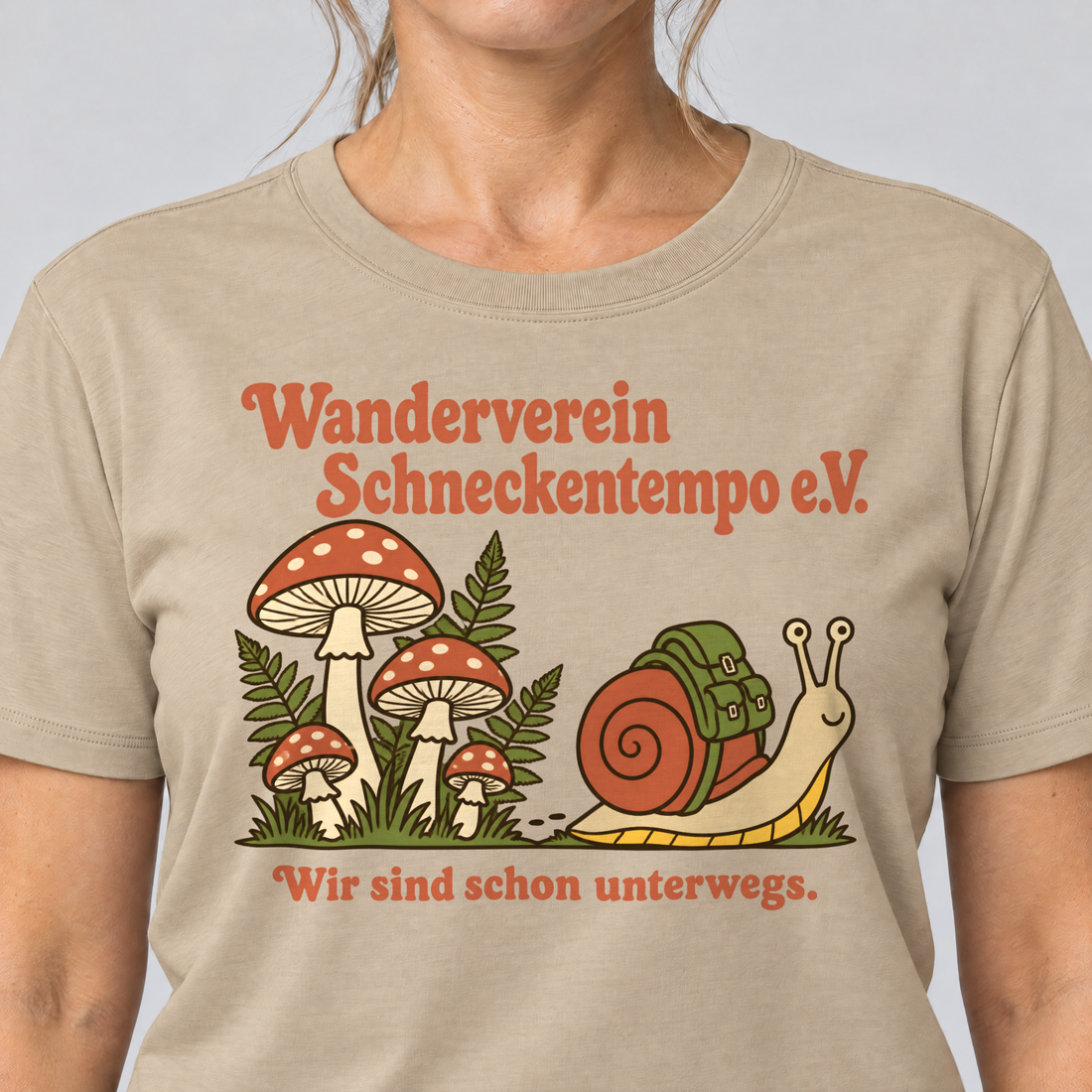 Nahaufnahme des Drucks: Wanderverein Schneckentempo – T-Shirt Unisex in Sand, von einer Frau getragen