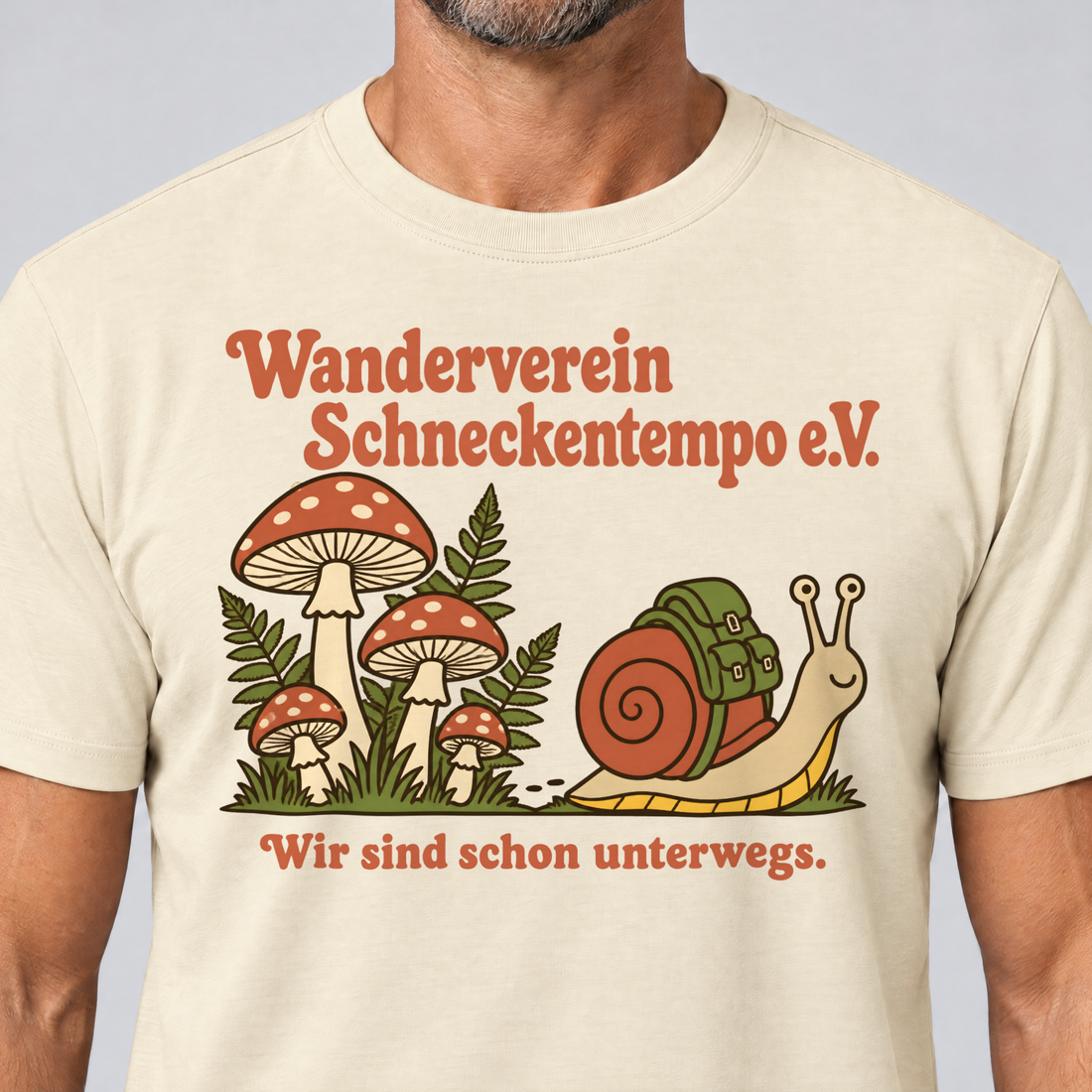 Nahaufnahme des Drucks: Wanderverein Schneckentempo – T-Shirt Unisex in Natur, von einem Mann getragen