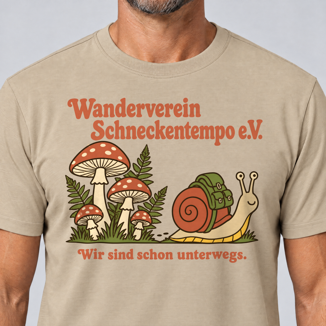 Nahaufnahme des Drucks: Wanderverein Schneckentempo – T-Shirt Unisex in Sand, von einem Mann getragen