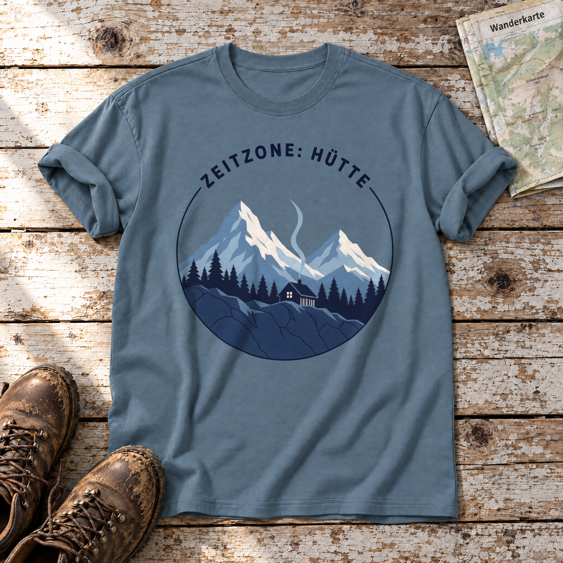 Zeitzone: Hütte – T-Shirt Unisex in Steinblau, flach liegend auf alten Holzbrettern mit Wanderschuhen und Wanderkarte.