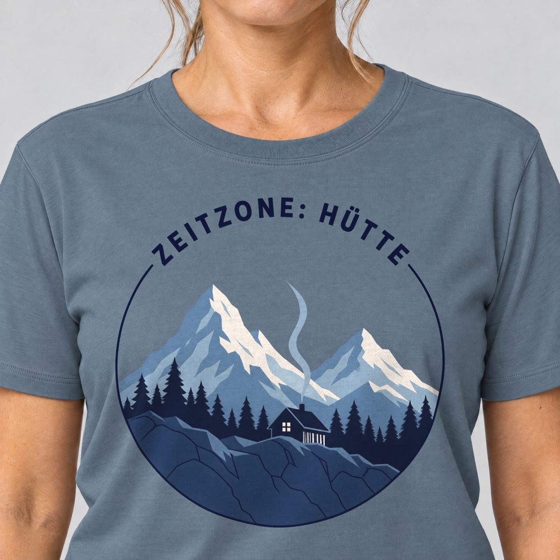 Nahaufnahme des Drucks: Zeitzone: Hütte – T-Shirt Unisex in Steinblau, von einer Frau getragen