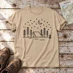 Zeltnacht – T-Shirt Unisex in Sand, flach liegend auf alten Holzbrettern mit Wanderschuhen und Wanderkarte.