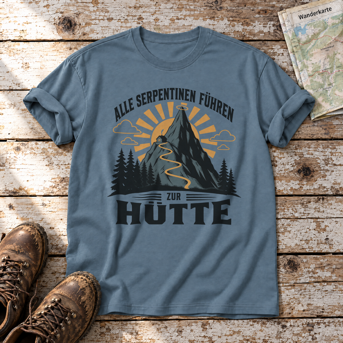 Alle Serpentinen führen zur Hütte – T-Shirt Unisex in Steinblau, flach liegend auf alten Holzbrettern mit Wanderschuhen und Wanderkarte.
