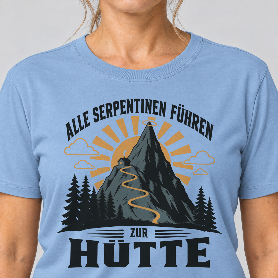Nahaufnahme des Drucks: Alle Serpentinen führen zur Hütte – T-Shirt Unisex in Himmelblau, von einer Frau getragen